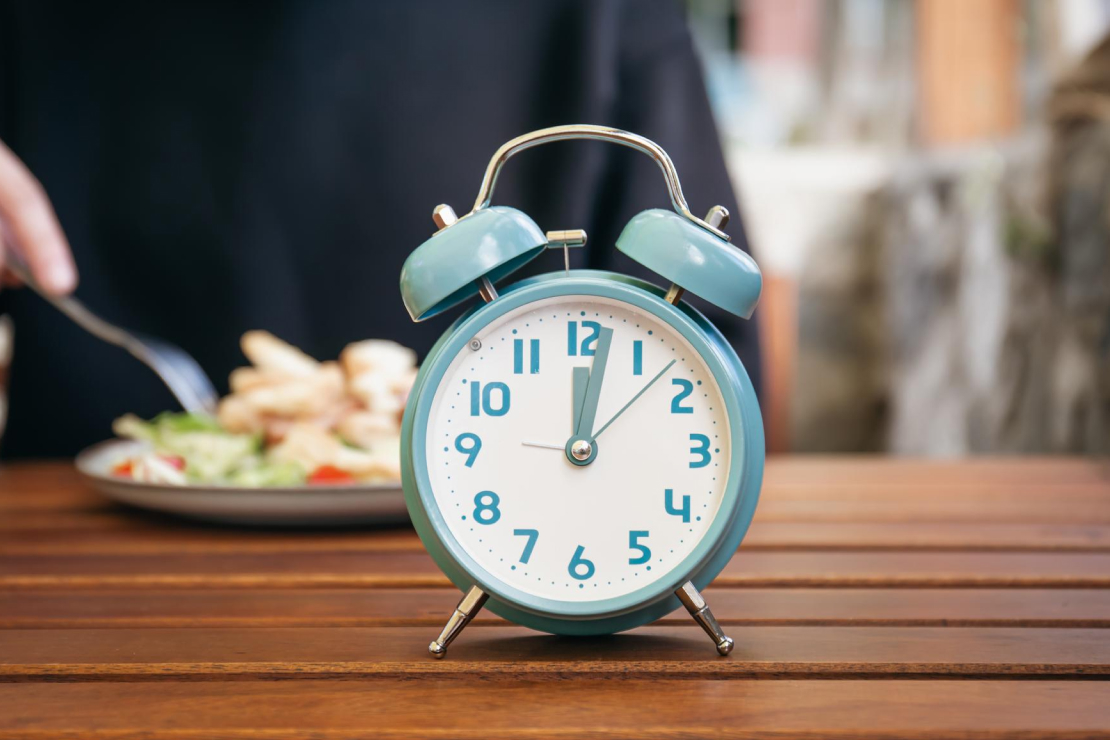 A woman eating a snack in bed at night, illuminated by a lamp, symbolizing late-night eating and its potential impact on hormone balance.