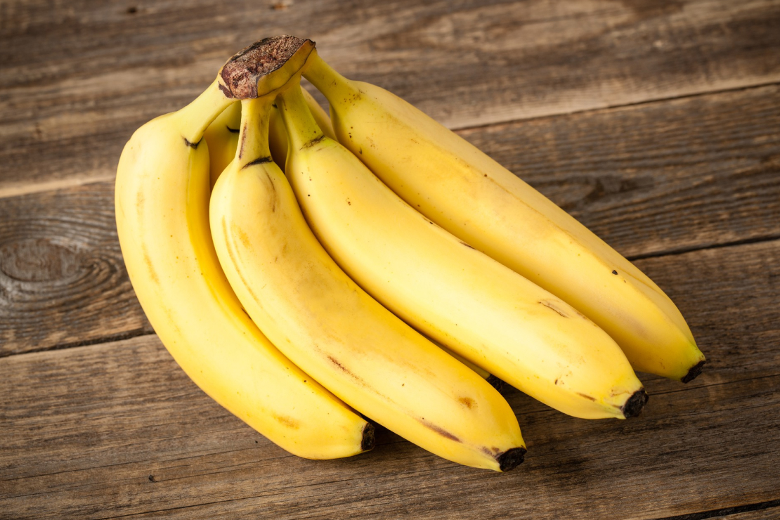 Ripe bananas next to a water bottle and gym towel, symbolizing pre-workout nutrition.