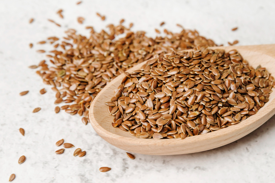 Flax seeds in a wooden bowl with a measuring spoon, symbolizing natural hormonal support.
