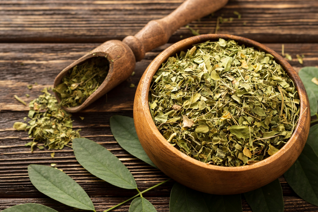 A traditional Yerba Mate gourd and bombilla straw sit next to a pile of loose-leaf mate and a modern glass of iced mate, showing its versatility.