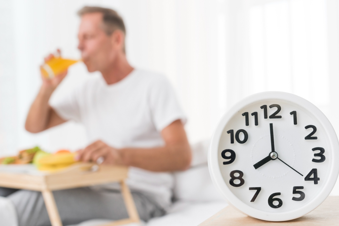 A person having an early breakfast with a clock showing morning hours, symbolizing reverse fasting