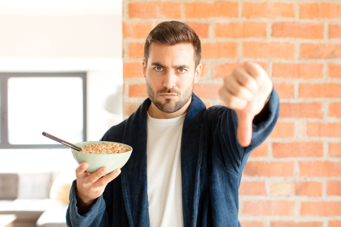 A man looking disapprovingly at his breakfast, symbolizing common protein goal mistakes.