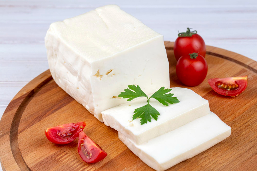 Crumbled feta cheese with cherry tomatoes and parsley, highlighting its fresh, tangy appeal.