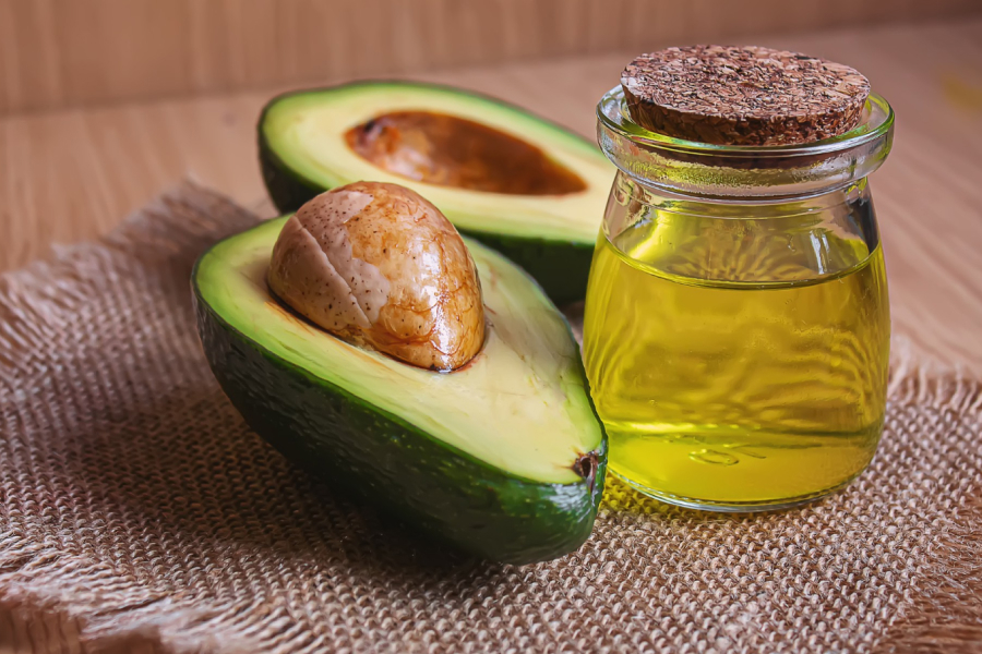 Fresh avocados and a bottle of avocado oil, emphasizing its natural source.